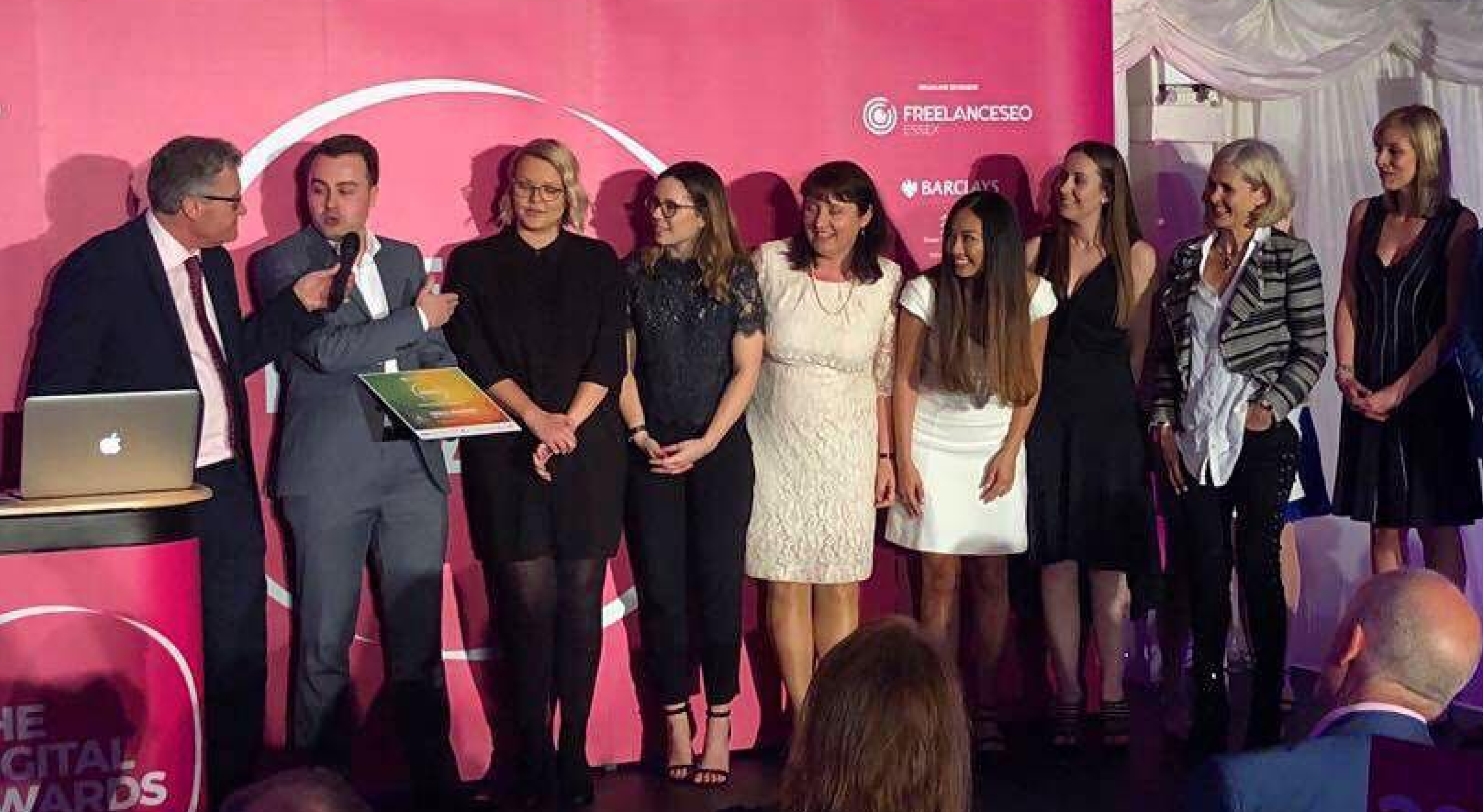 A line of people accepting an award and standing infront of a large banner for the Essex Digital Awards in 2018